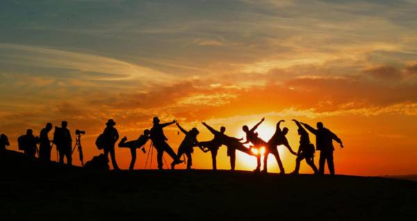 Gruppe springt im Gegenlicht der Sonne nach oben