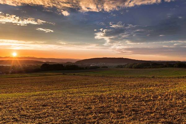 Sonnenaufgang auf Feld mit leichten Hügeln dahinter